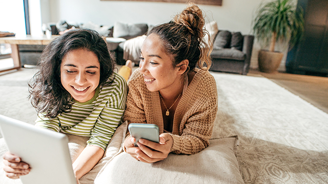 dos mujeres acostadas programando su debito automatico con Chevrolet Servicios Financieros en dispositivos mobiles